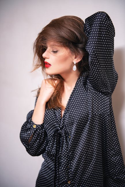 Stylish woman in polka dot outfit posing in a studio setting, showcasing modern elegance.